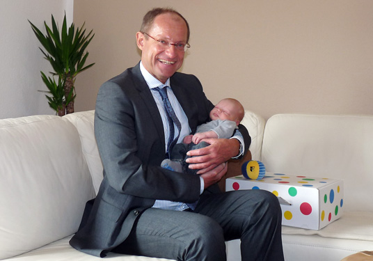 Das Bild zeigt Bürgermeister Ulrich Roland mit dem Baby Maximilian
