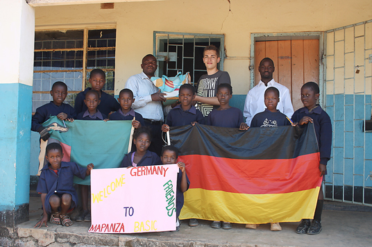 Das Bild zeigt, wie Marvin Wetekam dem stellvertretenden Schulleiter Mr. Ndambo das Gastgeschenk der Pestalozzischule überreicht