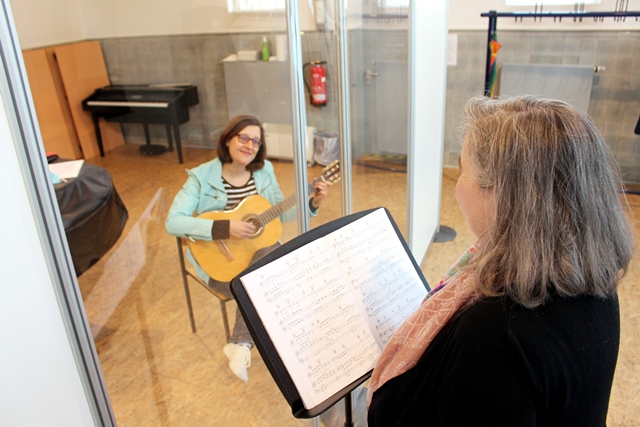 Durch Plexiglas getrennt: Musikschulleiterin Verena Voß (re.) und Mitarbeiterin Katharina Hörsting demonstrieren die Maßnahmen zur Hygiene für die Musikschule. Foto: Stadt Dülmen/Siemes
