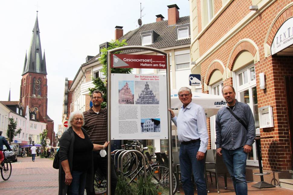 Bild vor dem Schild mit im Text genannten Vertretern. 
