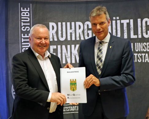 Gerd Rainer Scholze überreicht Bürgermeister Tesche symbolisch den Bauantrag.