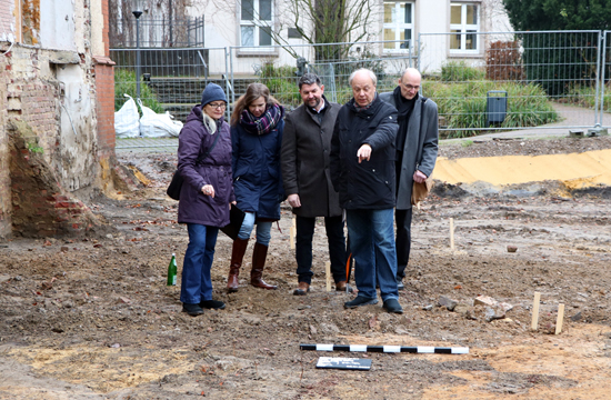 Heike Thamer, Planung Gebäudewirtschaft (v.l.n.r.), Denkmalpflegerin Luitgard Péron, Ralf Krietemeyer, Fachbereichsleiter Gebäudewirtschaft, der Erste Beigeordnete Georg Möllers und Architekt Krail vom Architekturbüro Krail und Leathley deuten auf die Konturen von Befunden, die deutlich zu erkennen sind.
