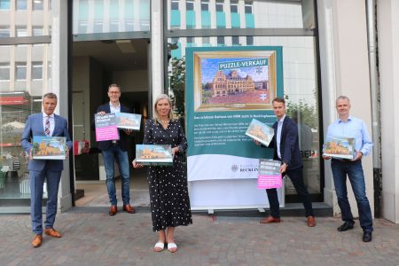 Für den Puzzle-Verkauf im ehemaligen Gerry-Weber-Shop am Altstadtmarkt werben (v. l.) Bürgermeister Christoph Tesche, Altstadt-Manager Jochen Sandkühler, Elke Fleckhaus (Kinderhospizdienst), Georg Gabriel (Abteilungsleiter Stadtmarketing) und Stefan Wilms Kuballa (Lebenshilfe). Foto: Stadt RE 