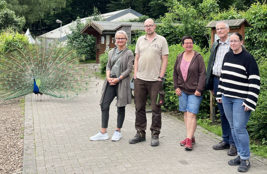 Neben dem Pfau freuen sich auch (v.l.) Vanessa Marczian (Team &bdquo;Auf ein Wort), Tierpfleger Oliver Langner, Sabine Sitko (Team &bdquo;Auf ein Wort), Pr&auml;dikant Peter Herkenrath und Tanja Wember (Team &bdquo;Auf ein Wort&ldquo;) auf den Gottesdienst im Tierpark.