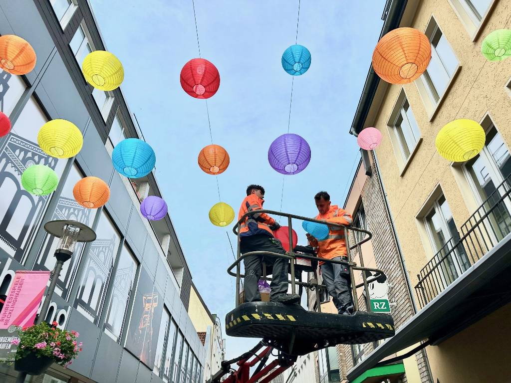 KSR-Elektriker Vasil Stojani und der Auszubildende Can Maurice Lutsch installierten an der Große Geldstraße die ersten bunten Lampions. Foto: Stadt RE