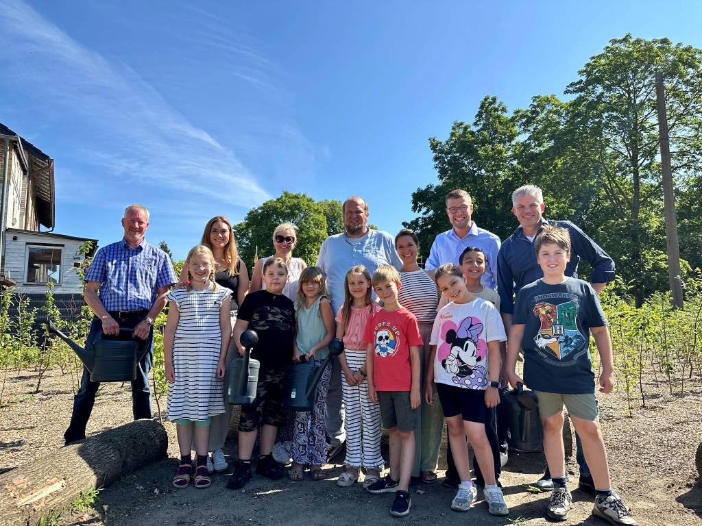 Schüler*innen der Grundschule Hochlarmark gießen ihren Tiny Forest mit Unterstützung von Beigeordnetem Axel Fritz (r.), Klimaanpassungsmanager Felix Sprenger (2. v. r.), Michael Godde vom Fachbereich Mobilität, Stadtgrün und Straßenbau (l.), Schulleiter Dr. Thomas Czerwinski (m.) und Lehrerinnen der Schule
