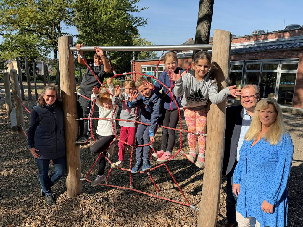 Schulleiterin Britta Richta (li.), Schuldezernent Dr. Sebastian Sanders und Christine von Bobart (Abteilungsleiterin Schule) begutachten gemeinsam mit Kindern eines der Spielgeräte auf dem Außengelände der Ortlohschule.