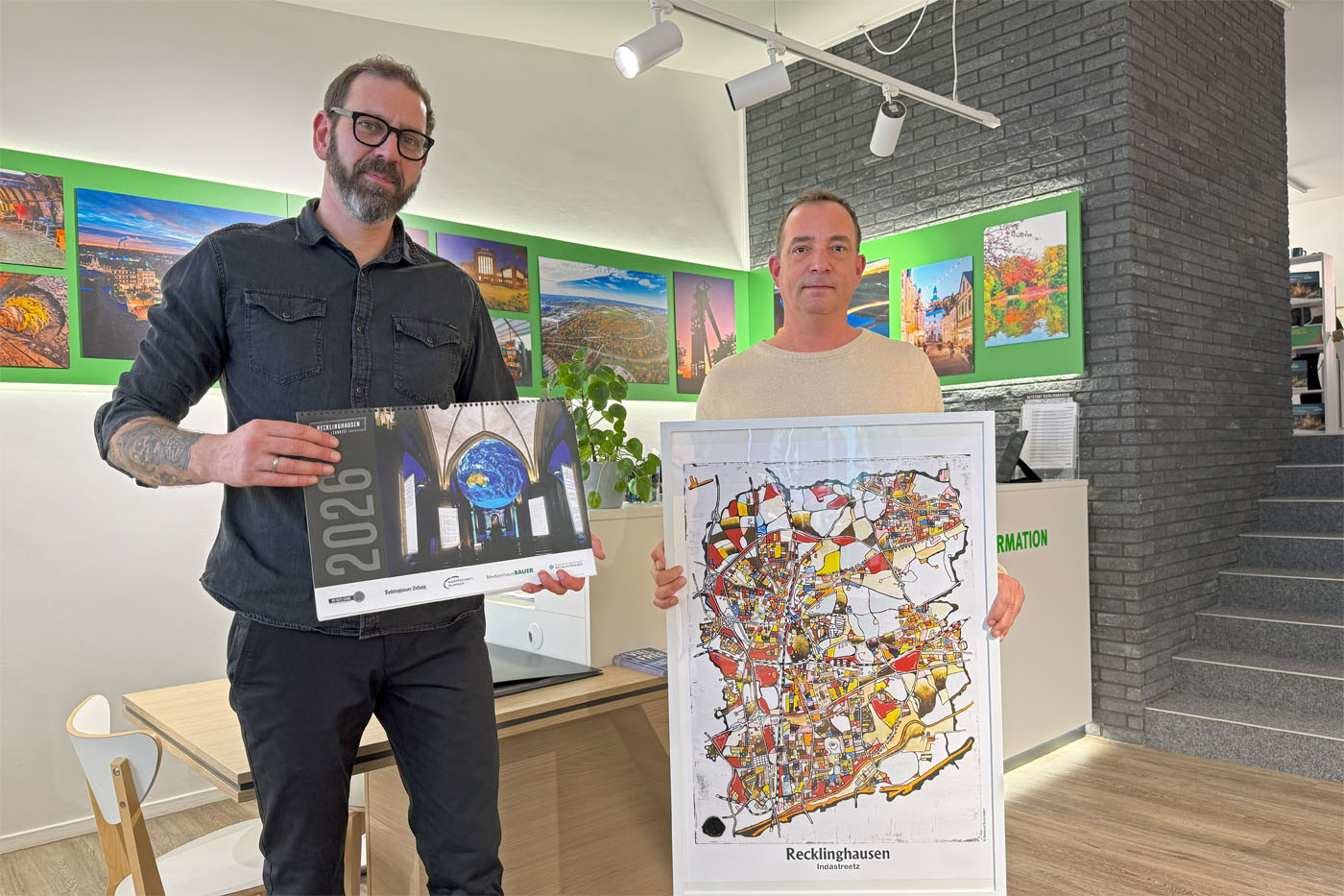 Tim Rimprecht (li.), Leiter der Tourist Information, und K&uuml;nstler Roland Schr&ouml;der pr&auml;sentieren den RE-leuchtet-Kalender sowie einen der Kunstdrucke. 