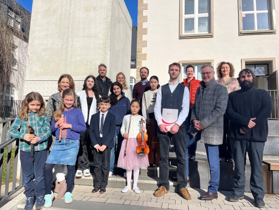 Pressefoto: Die Gewinner*innen des Regionalwettbewerbs mit ihren Lehrkr&auml;ften sowie B&uuml;rgermeister Axel Tschersich (2. v. r., vorne) und Kristin Seifert, Leiterin der Musikschule (2. v. l., hinten)