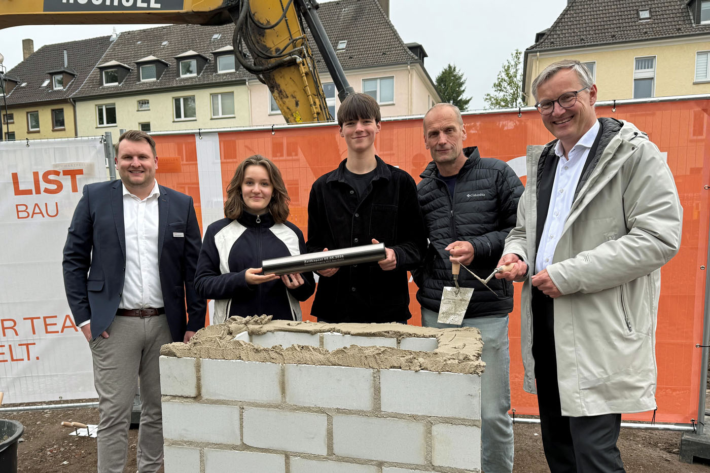 Marvin Stenvers, Gesch&auml;ftsf&uuml;hrer LIST Bau Nordhorn, Sch&uuml;lersprecherin Mia Majstorovic, Sch&uuml;lersprecher Ferdinand Feldbr&uuml;gge, Schulleiter Christian Passerah und B&uuml;rgermeister Axel Tschersich (v.li.) mauerten eine Zeitkapsel in den Grundstein ein. Foto: Stadt RE