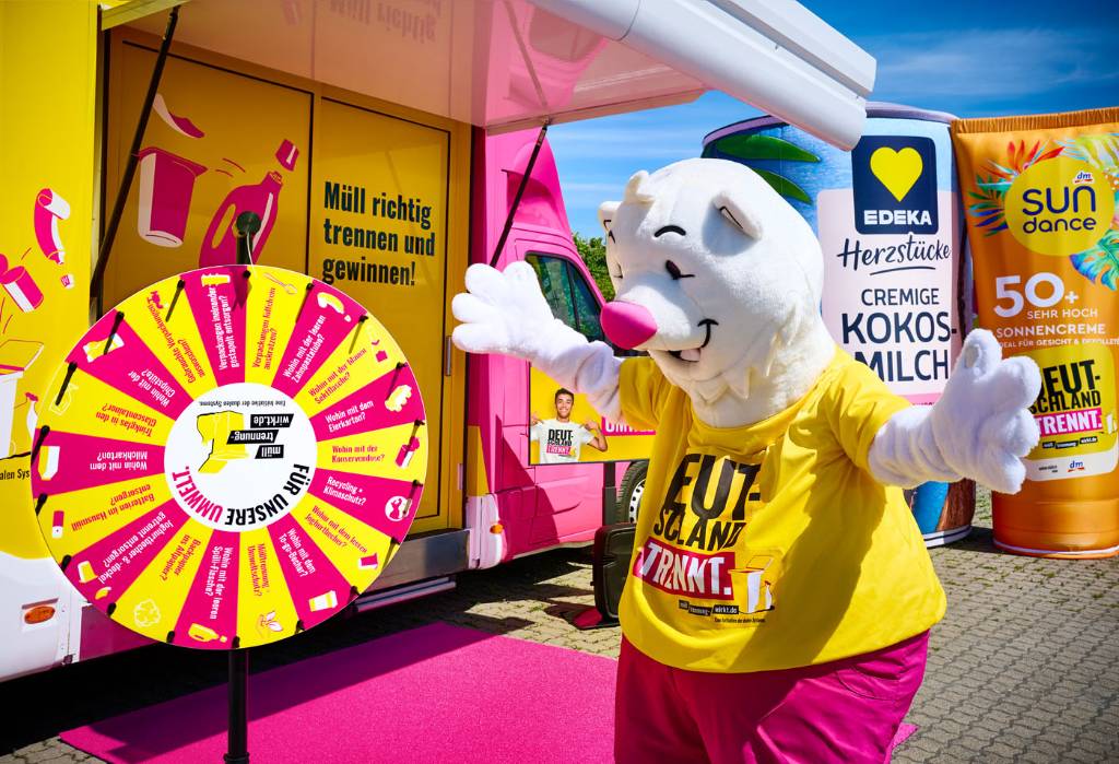 An einem Showtruck wird am Aktionstag auf dem Altstadtmarkt &uuml;ber richtige M&uuml;lltrennung informiert. Mit dabei ist Maskottchen &bdquo;Trenn-B&auml;r&ldquo;. Foto: Deutschland trennt