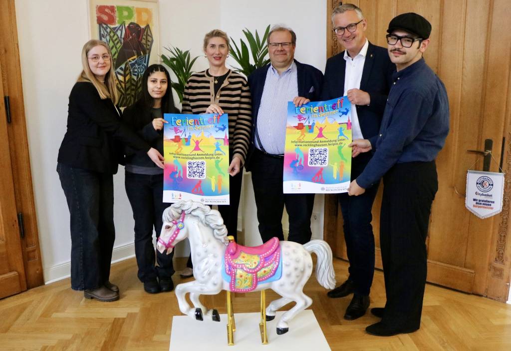B&uuml;rgermeister Axel Tschersich (2.v.r.) pr&auml;sentiert gemeinsam mit (v.l.) Pia Kowatsch (Fachbereich Kinder, Jugend und Familie), Romaf Muhamad (Kinder- und Jugendparlament), Fachbereichsleiterin Carmen Greine, Dezernent Dr. Sebastian Sanders und Alan Hasan (Kinder- und Jugendparlament) das Plakat zum Ferientreff. Foto: Stadt RE