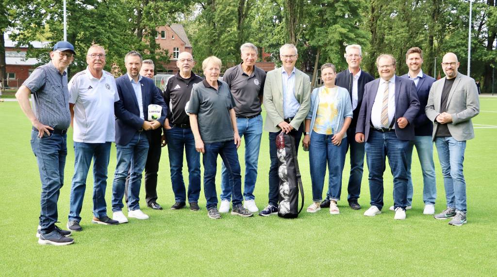 B&uuml;rgermeister Axel Tschersich (6.v.r.), Uwe Matecki (7.v.r./Vorsitzender SW R&ouml;llinghausen) und Werner Fimpeler (6.v.l./stellv. Vorsitzender des Stadtsportverbands) er&ouml;ffneten gemeinsam mit Vertreter*innen der Verwaltung, der Politik und des Sports den neuen Kunstrasenplatz in R&ouml;llinghausen. Foto: Stadt RE