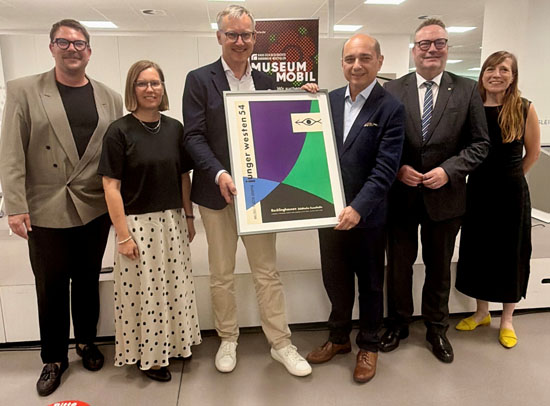 Ein Originalplakat aus dem Jahr 1954 &uuml;berreichten B&uuml;rgermeister Axel Tschersich (3. v. l.), Museumsleiter Dr. Nico Anklam, Kerstin Weber (wissenschaftliche Mitarbeiterin Kunsthalle) an Stiftungspr&auml;sident Basil Kerski und Projektleiterin Dr. Stefanie Johnen (v. l.). An der Er&ouml;ffnungsveranstaltung nahm auch Landrat Bodo Klimpel teil. Foto: Stadt RE