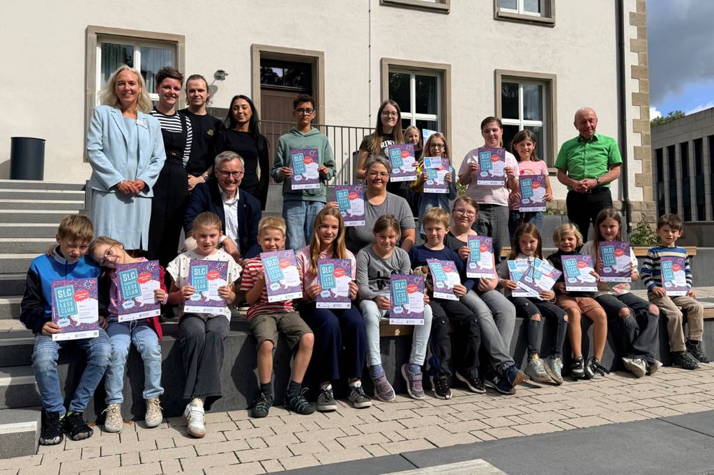 Organisator*innen des Sommerleseclubs, Bürgermeister Axel Tschersich und Teilnehmer*innen mit ihren Urkunden auf den Treppen am Willy-Brandt-Haus. Foto: Stadt RE